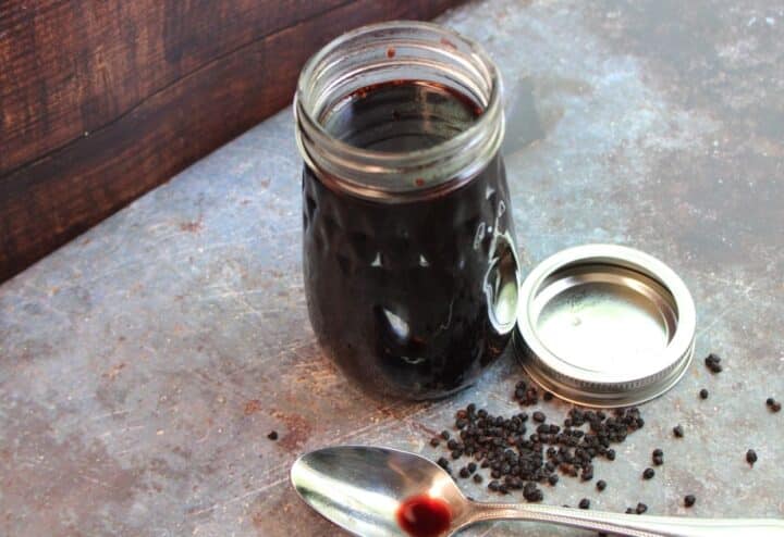A jar of black pepper sauce with a spoon next to it.