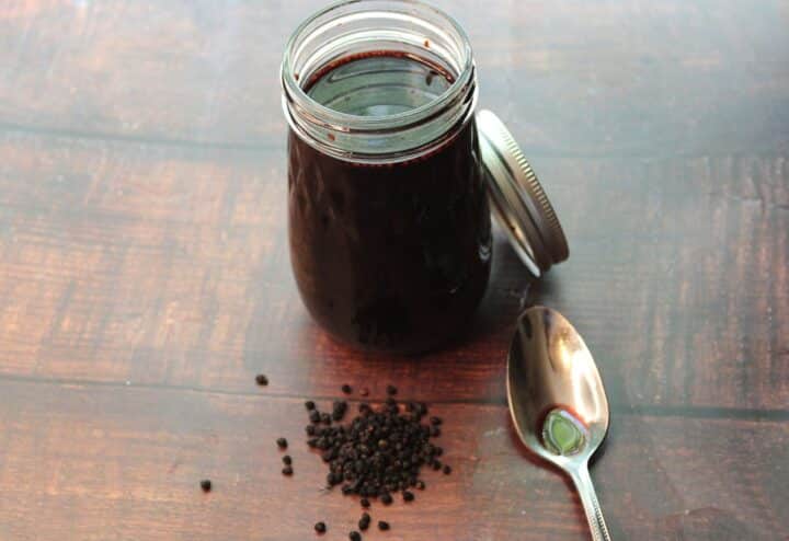 A jar of black pepper with a spoon next to it.