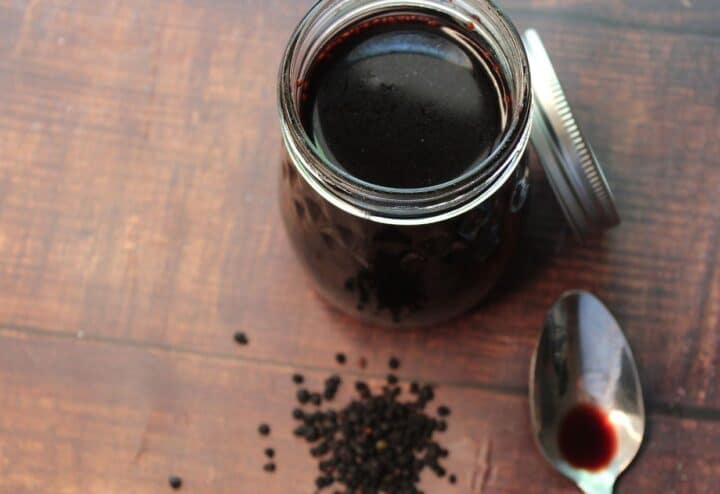 A jar of black pepper sauce with a spoon next to it.