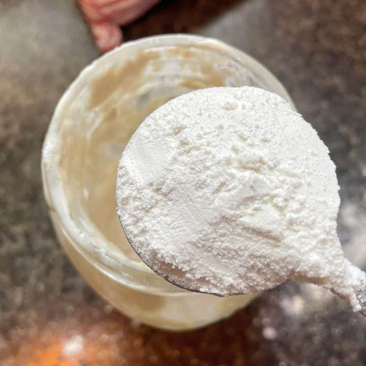 Feeding a jar of sourdough discard starter with more flour.