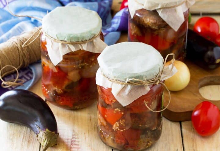 Three jars of pickled vegetables on a wooden table.