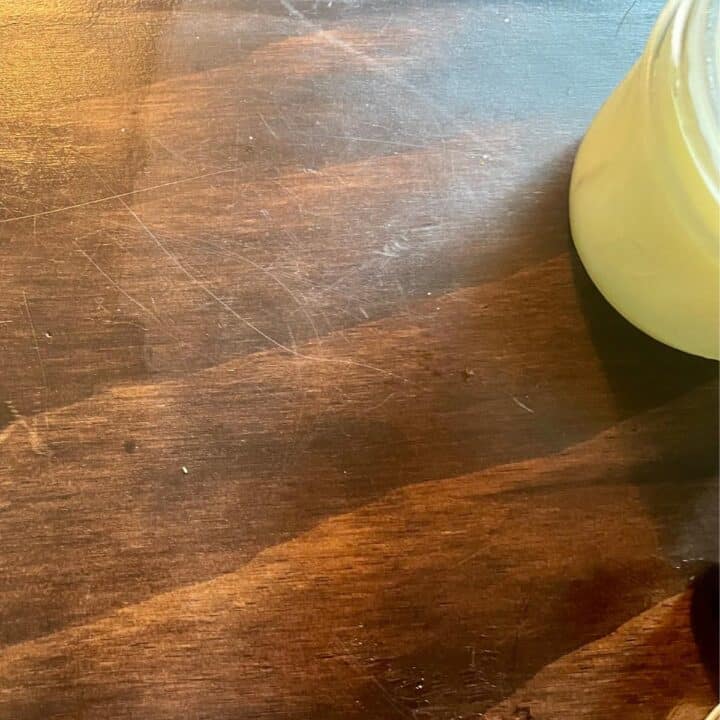 A jar of lemon beeswax polish on a wooden table.