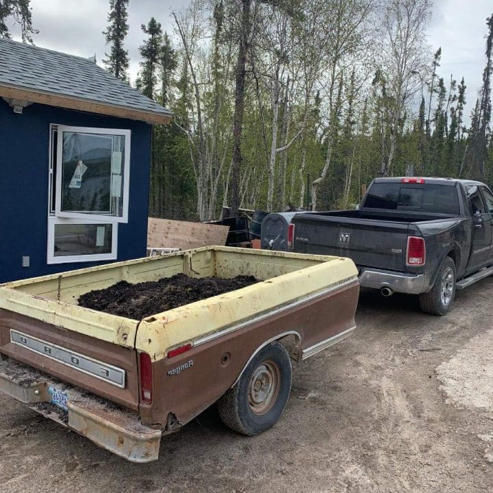 A truck parked on a dirt driveway full of garden soil ready for compost mix.