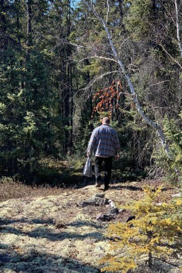 A man walking through the woods with a backpack.