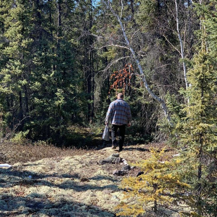 A man walking through the woods with a backpack.
