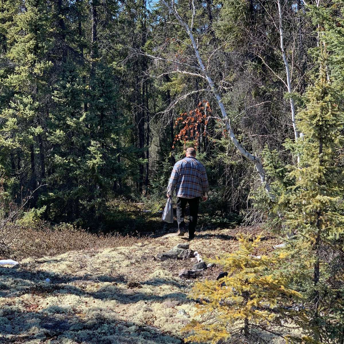 A man walking through the woods with a backpack.