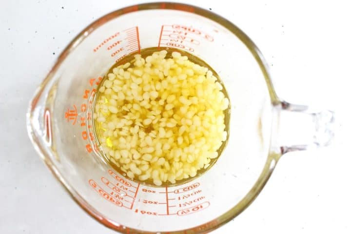 Top view of a measuring cup containing small white grains soaking in liquid.