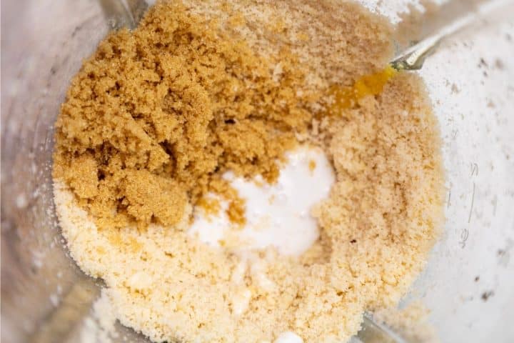 Blender container with brown sugar, an egg yolk, and a liquid ingredient before mixing.