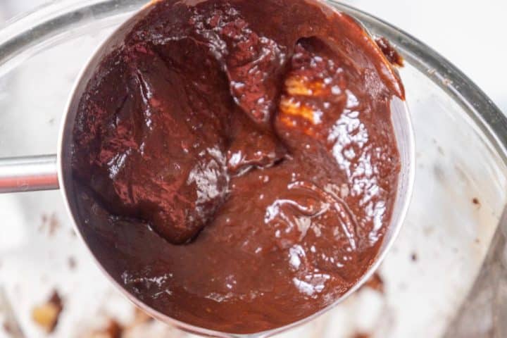 Close-up of a metal mixing bowl containing thick, glossy chocolate batter.