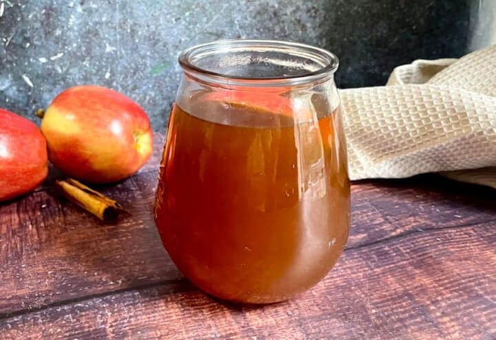 A jar of apple cider on a wooden table.