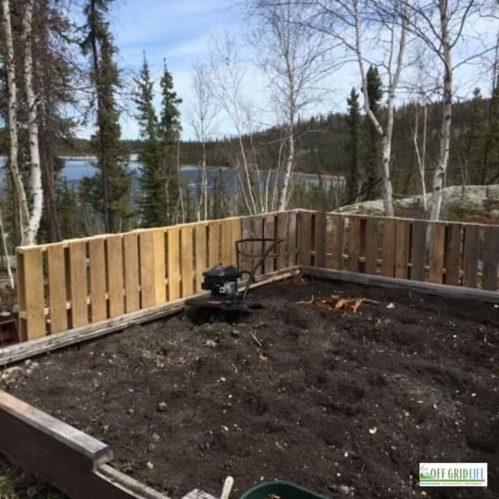a tilled garden bed surrounded by a pallet fence