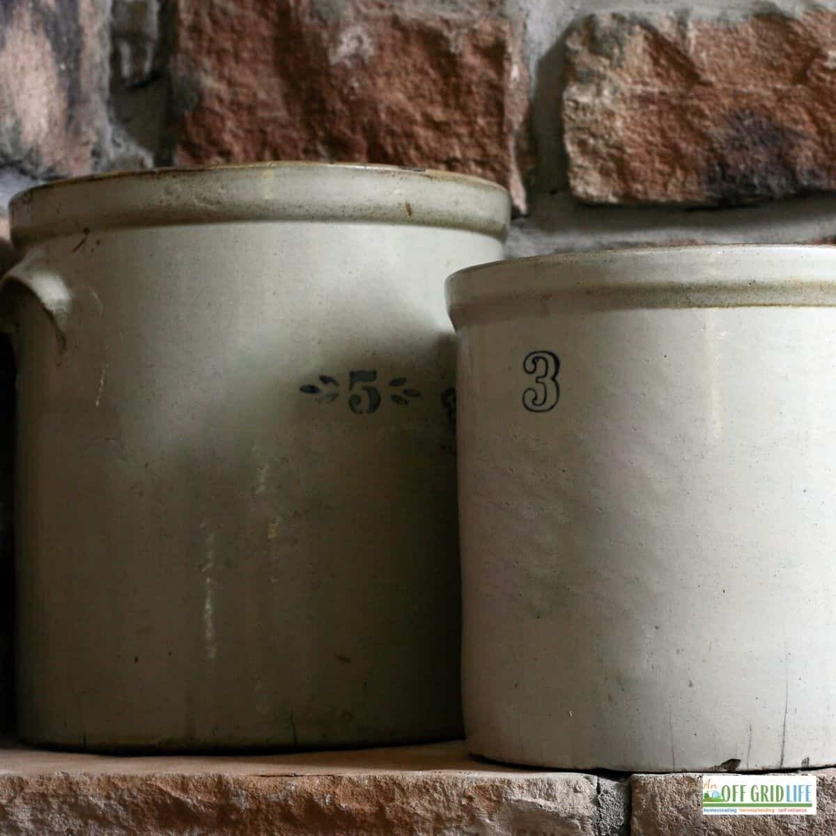two white stone crocks with a brick wall background