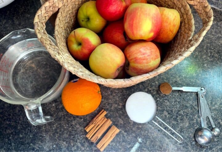 A basket of apples, oranges, and spices on a counter.