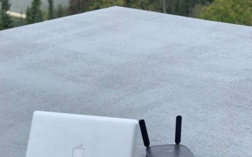 a laptop and router on a roof of an off grid cabin