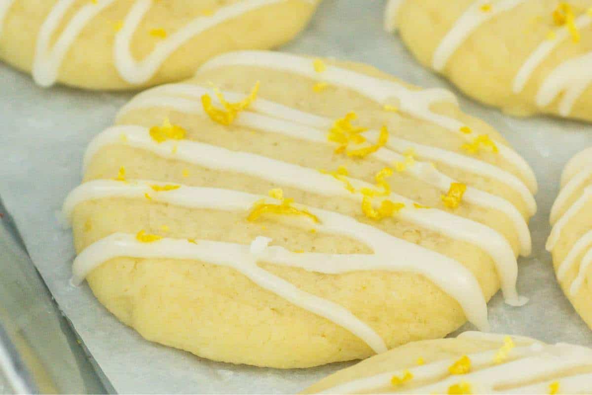 Freshly baked lemon meltaway cookies with white icing and lemon zest on top.