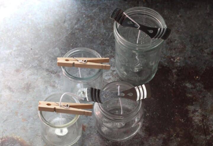 Three jars with clothespins on top of them.