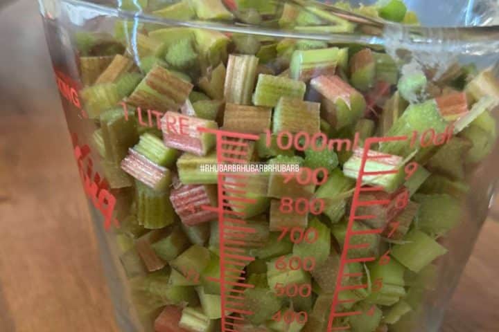 Chopped rhubarb in a measuring cup, filling up to the 800 ml mark, with a focus on the vibrant green and red pieces.