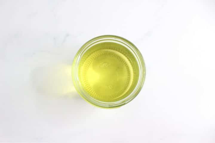 A clear glass bowl containing yellow liquid, viewed from above, on a white background.