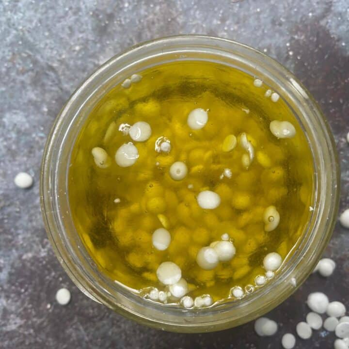 Olive oil in a jar with beeswax pellets.