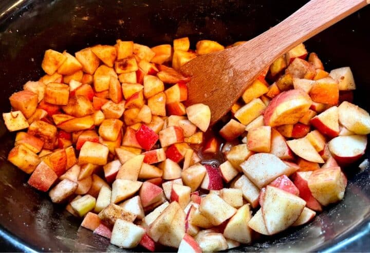 Apples in a pot with a wooden spoon.