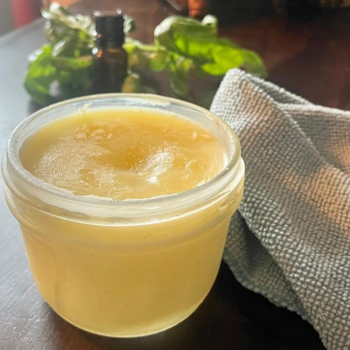 A jar of lemon beeswax furniture polish on a wooden table.