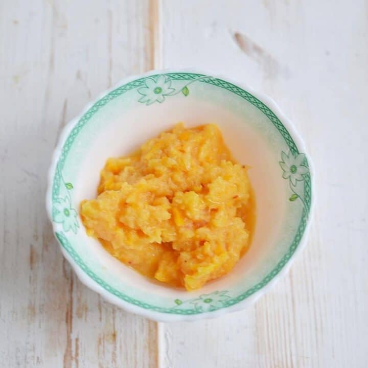 Shredded whole orange in a bowl for cranberry orange relish.