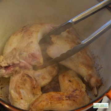 rabbit legs and breasts being browned in a cast iron dutch oven