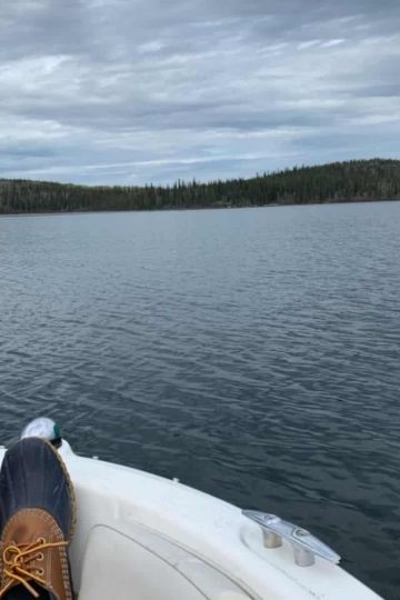 a picture off grid of someones feet up on a boat looking at open water.