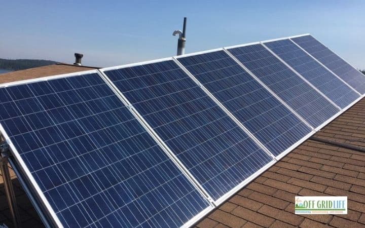 a five panel solar array on a brown shingle roof with a blue sky background