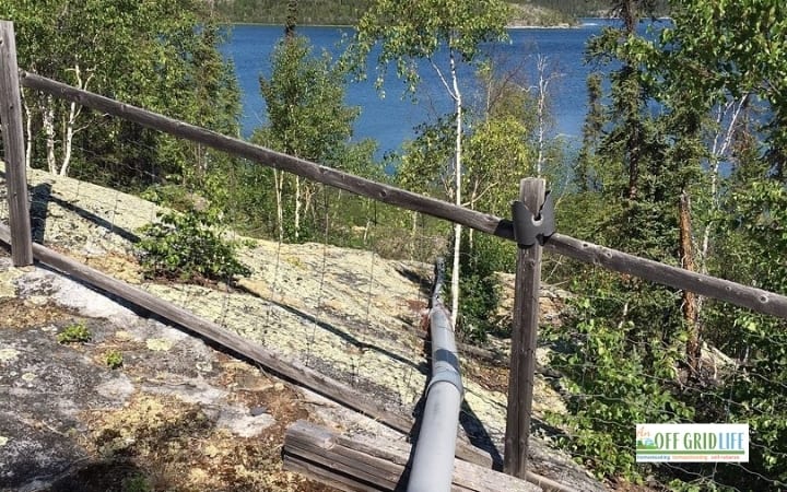 Our diy off grid water supply system above ground pipe going over rock down to the lake