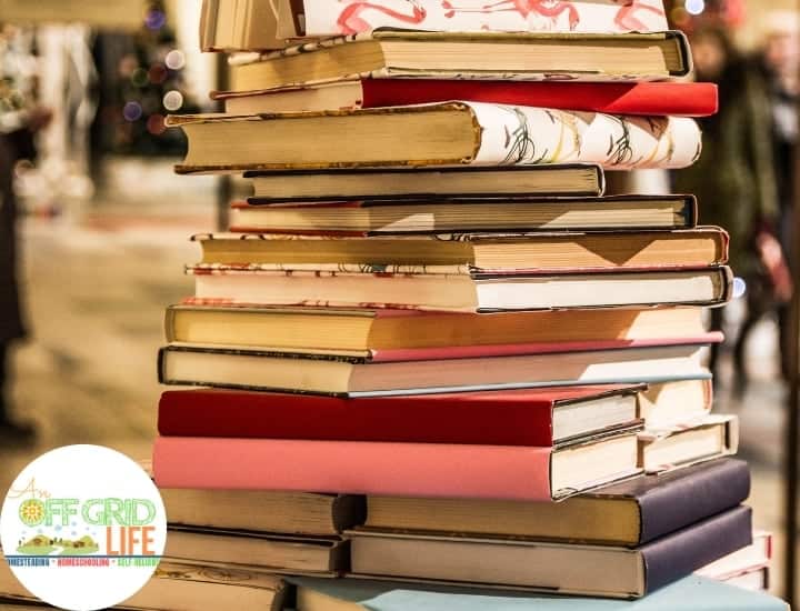 An old-fashioned stack of children's Christmas books on a table near a Christmas tree.