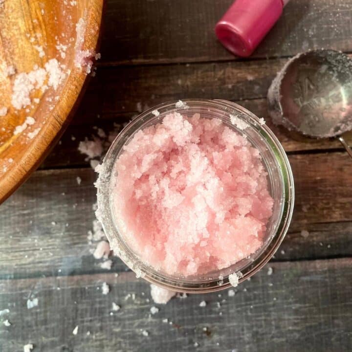 Pink peppermint scrub in a jar on a wooden table.