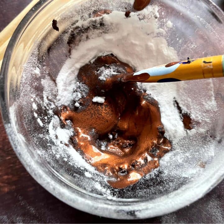 Chocolate ganache in a glass bowl with a spoon.
