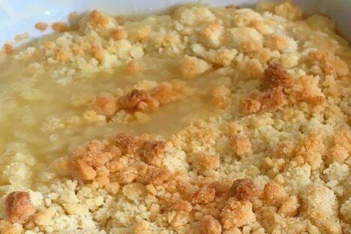 A close-up of a peach crumble dessert with a golden-brown crumbly topping.