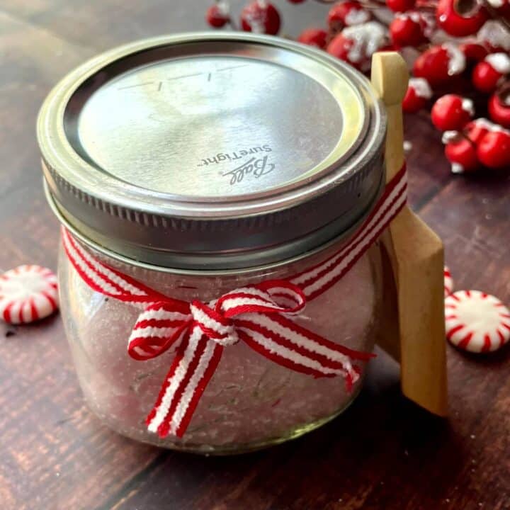 A jar of peppermint foot scrub with a wooden spoon.