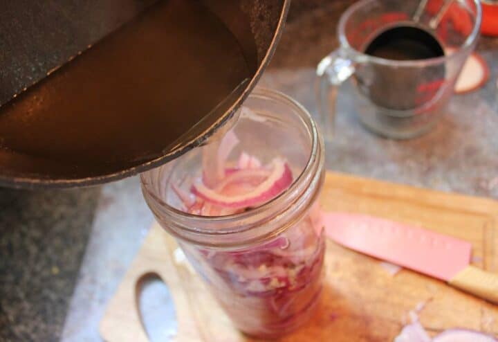 Pouring apple cider vinegar mixture into red onions mixture