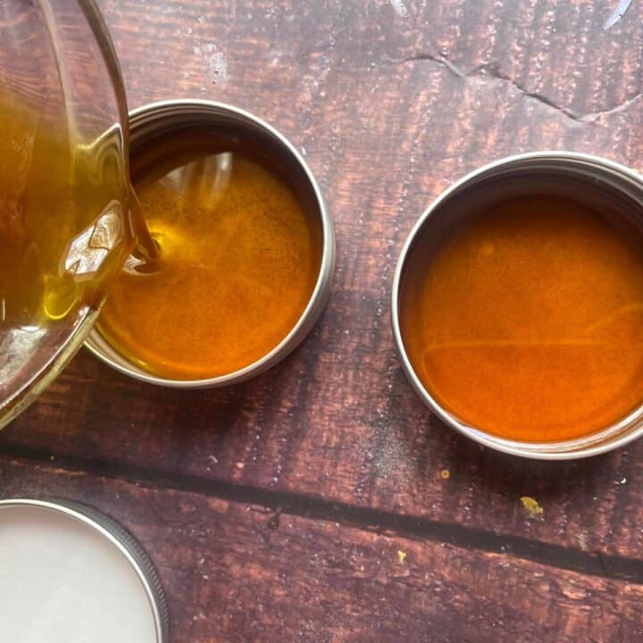 Two tins of honey being poured into a wooden table.