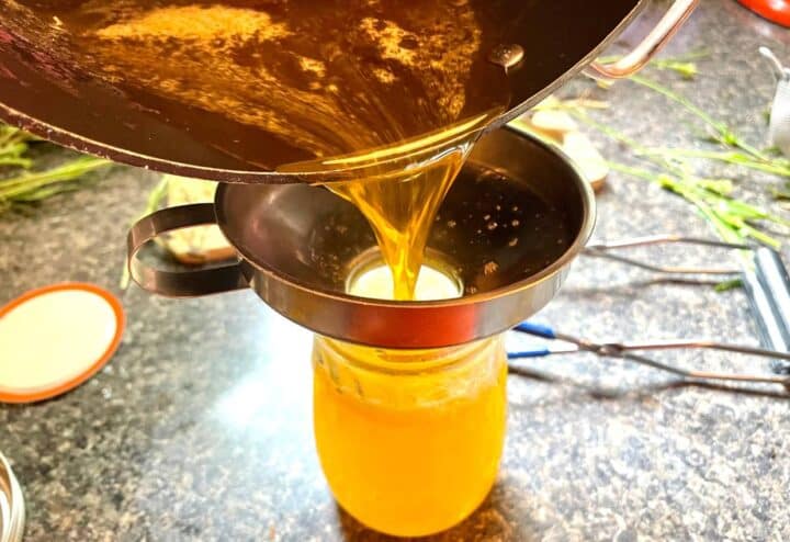 Pouring prepared jelly into jar for water bath canning.