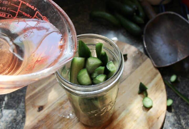 Pouring vinegar over sliced cucumbers