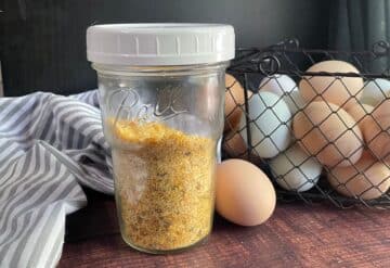 Dehydrated eggs in jar with basket of fresh eggs behind.