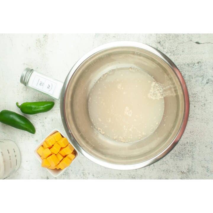 A bowl of water and yeast liquid with ingredients next to it.