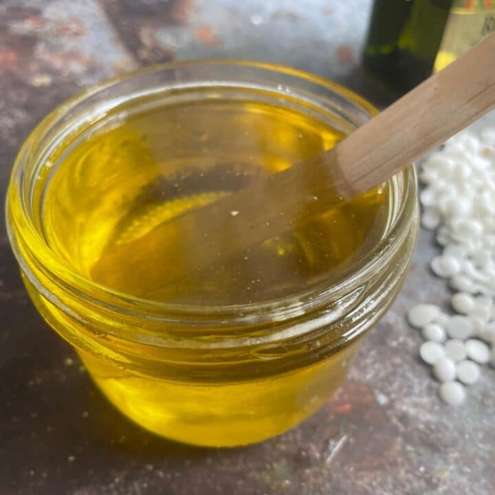 A jar of homemade beeswax furniture polish with a wooden spoon.