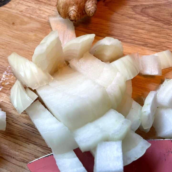 Sliced onions and ginger on a cutting board.