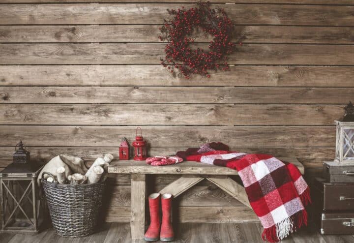 A wooden bench with a red blanket and a wreath on it.