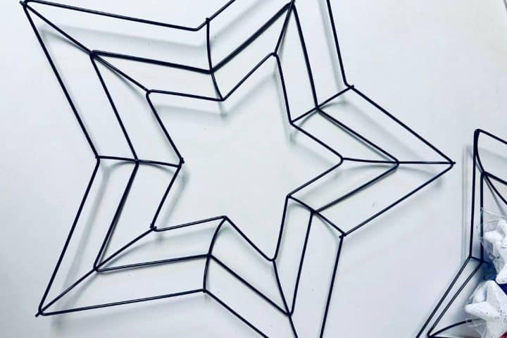 Three wireframe star shapes placed on a white surface, arranged in a way that two larger stars partially overlap and a smaller star is in close proximity.