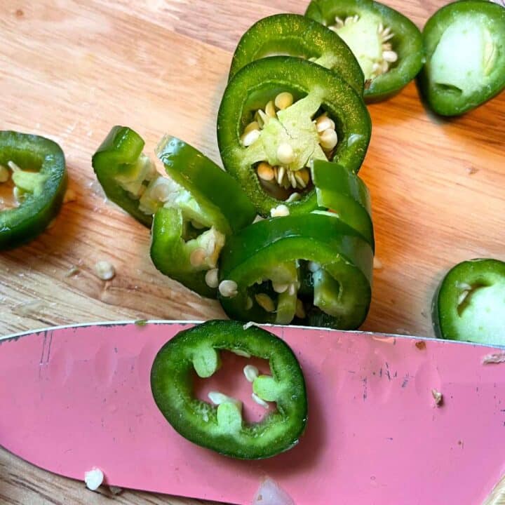 Sliced jalapeno peppers on a cutting board.