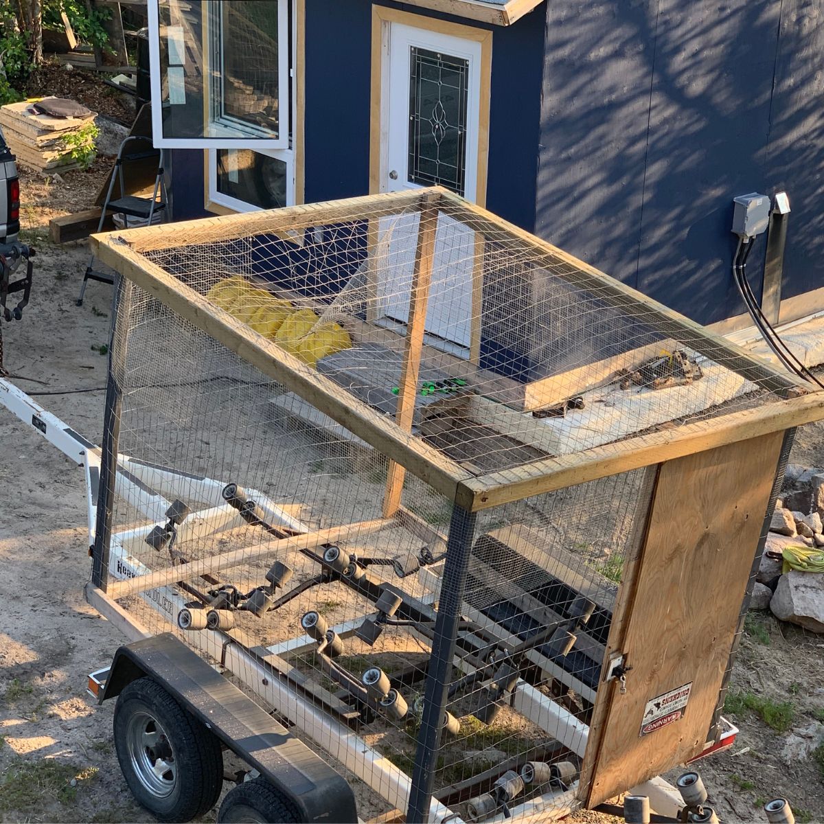 A chicken coop on a trailer in front of a house.