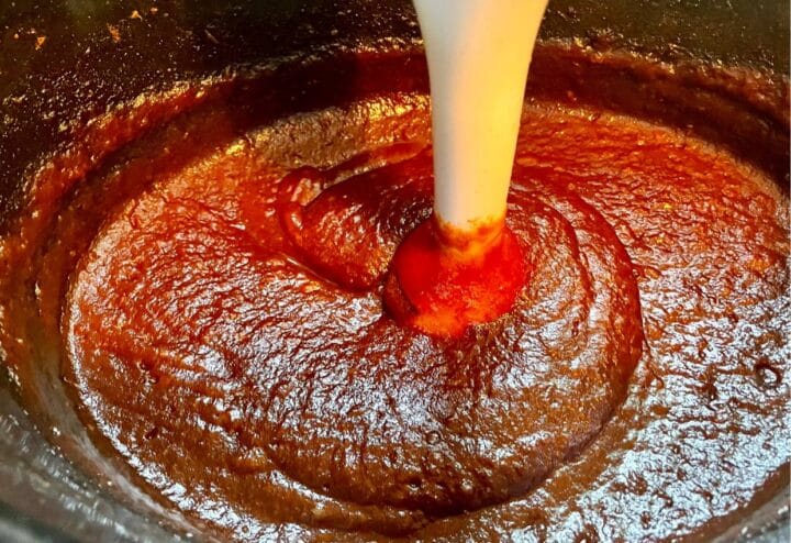 A sauce being poured into a pot.