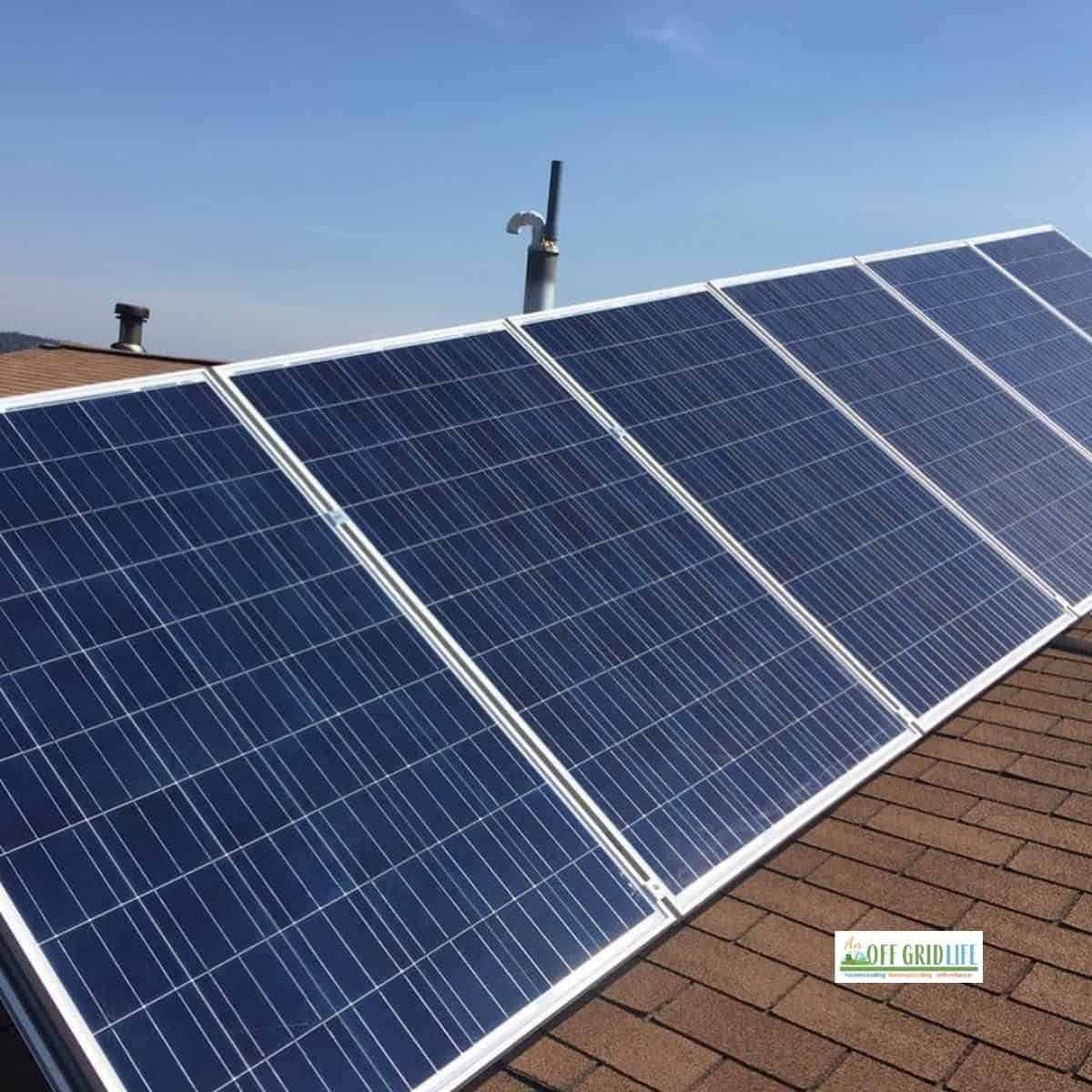 a five panel solar array on a brown shingle roof with a blue sky background