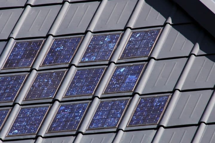 Close-up of a roof with integrated solar panels, each panel embedded within the roof tiles, arranged in a grid pattern.